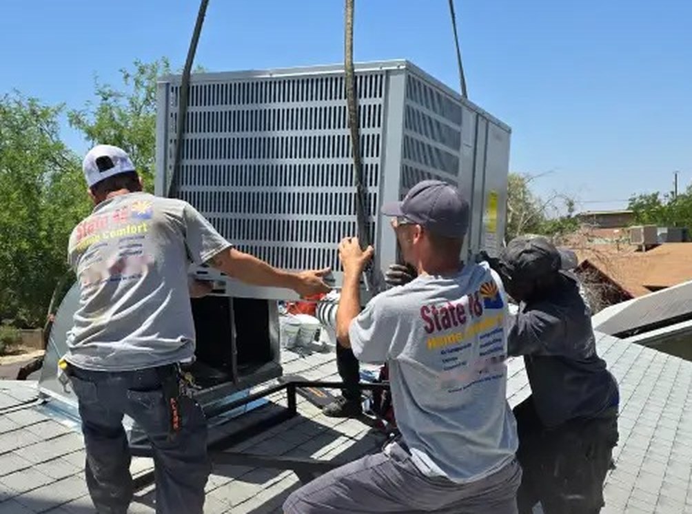 Three State Forty Eight technicians guiding a rooftop air conditioning unit into place on a Peoria home