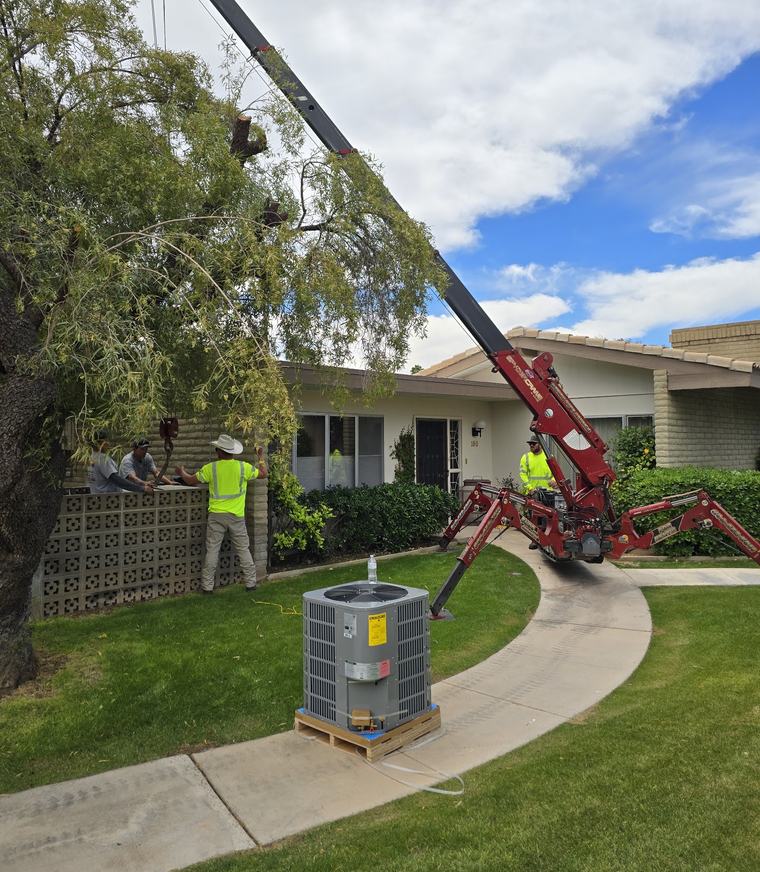 Crane setting a new condensing unit on its pad while a State Forty Eight technician guides it in